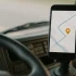 Smartphone with GPS map and orange route pin in truck cab top-right showing real-time shipment tracking.